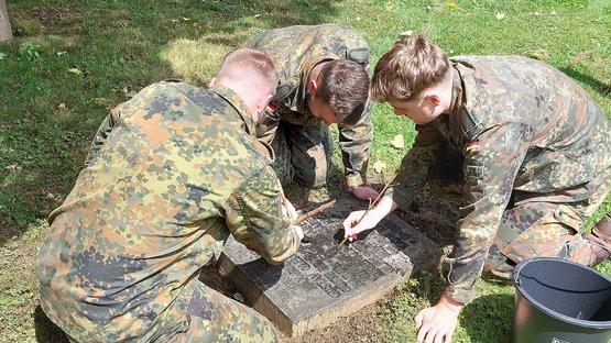 Auf dem Gräberfeld für die Bombenopfer befreien die Soldaten die Namensinschriften von Moos Soldaten reinigen ein Kriegsgrab auf dem Kasseler Hauptfriedhof