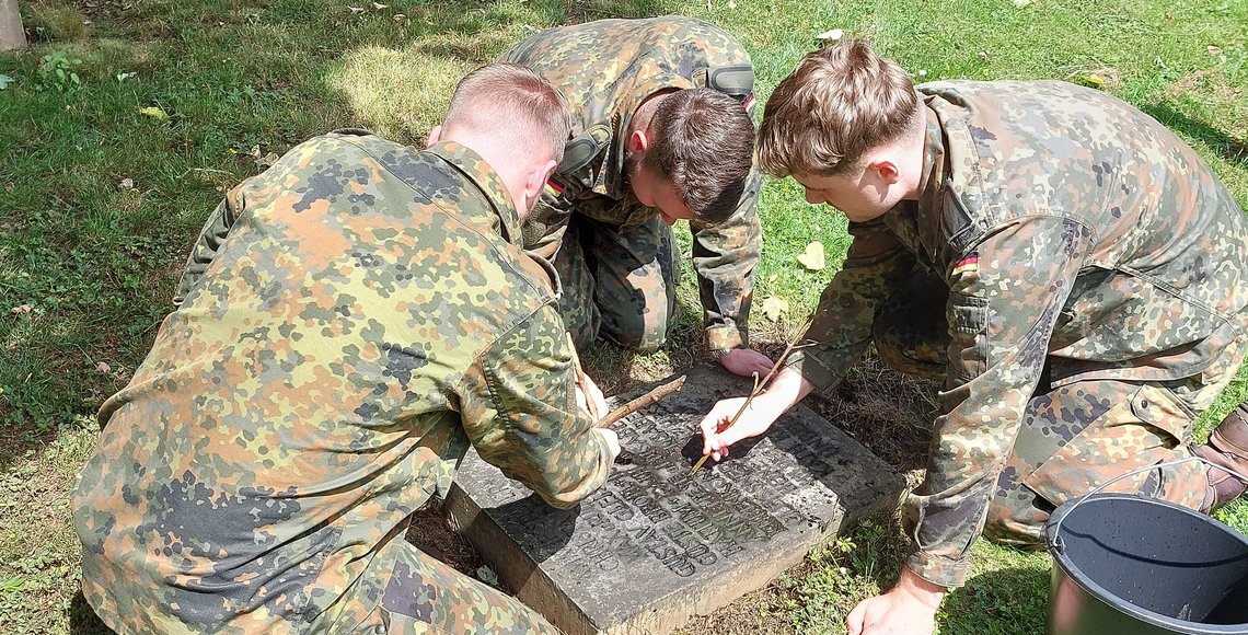 Soldaten reinigen ein Kriegsgrab auf dem Kasseler Hauptfriedhof