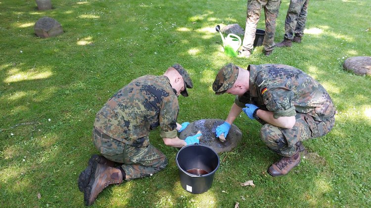 Bundeswehrsoldaten reinigen einen Grabstein auf dem Kasseler Hauptfriedhof